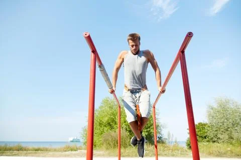Young man exercising on parallel bars outdoors Stock Photos