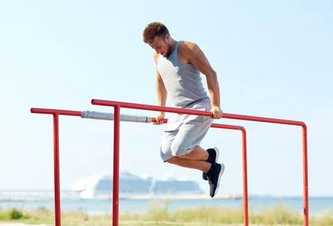 Young man exercising on parallel bars outdoors Stock Photos