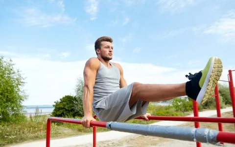 Young man exercising on parallel bars outdoors Stock Photos