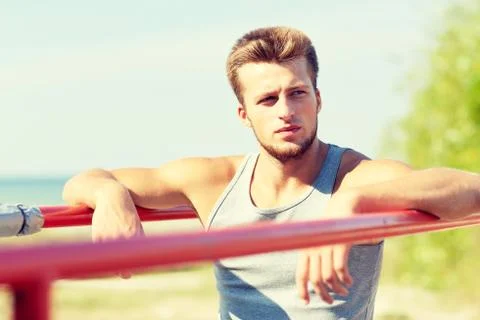 Young man exercising on parallel bars outdoors Stock Photos