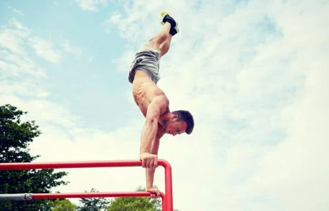 Young man exercising on parallel bars outdoors 写真素材