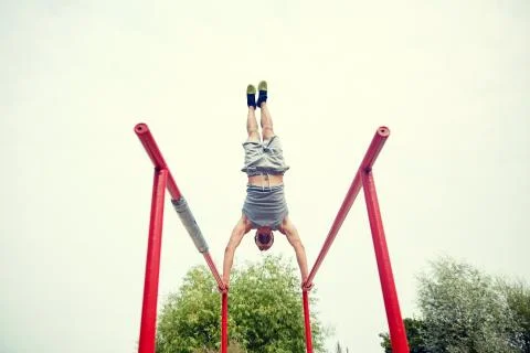 Young man exercising on parallel bars outdoors Stock Photos