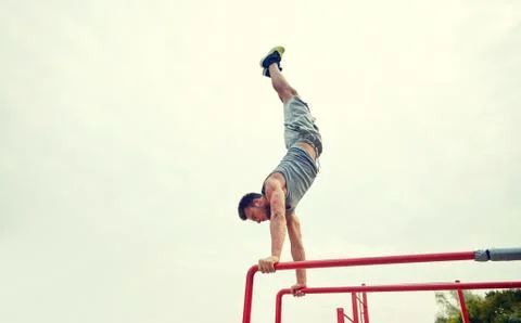 Young man exercising on parallel bars outdoors Stock Photos