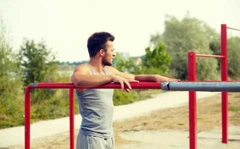 Young man exercising on parallel bars outdoors Stock Photos