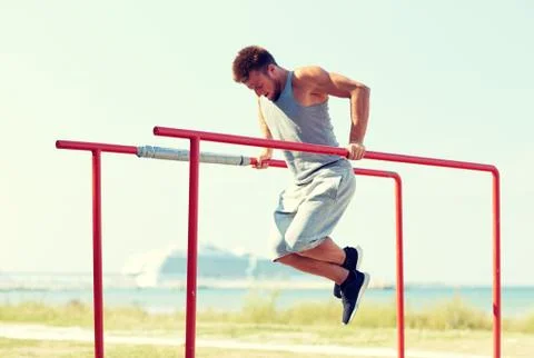 Young man exercising on parallel bars outdoors Stock Photos
