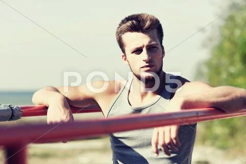 Young man exercising on parallel bars outdoors Stock Photos