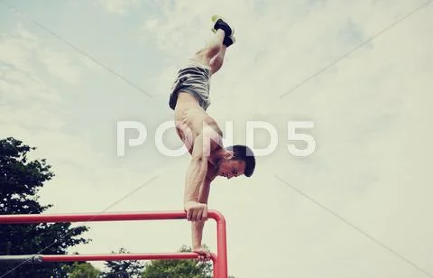 Young man exercising on parallel bars outdoors Stock Photos