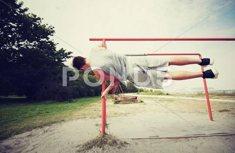 Young man exercising on parallel bars outdoors Stock Photos