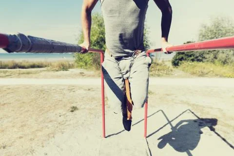 Young man exercising on parallel bars outdoors Stock Photos