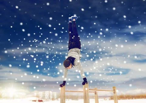 Young man exercising on parallel bars in winter Stock Photos