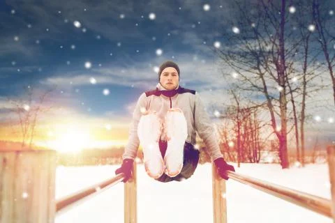 Young man exercising on parallel bars in winter Stock Photos