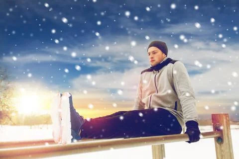 Young man exercising on parallel bars in winter Stock Photos