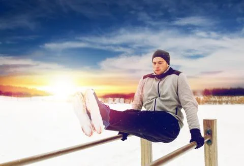 Young man exercising on parallel bars in winter Stock-Fotos