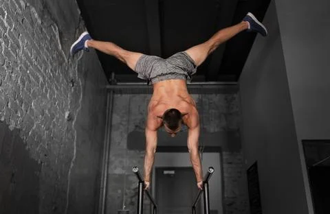Young man exercising on parallel bars in gym Stock-Fotos