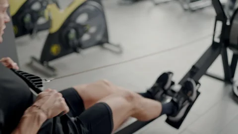 Young Man Exercising on a Rowing Machine in Modern Gym Stock Footage 315283224