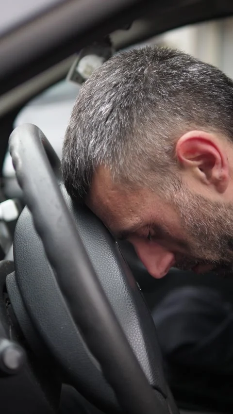 Young man exhausted in car resting head on steering wheel Stock Footage 332417959