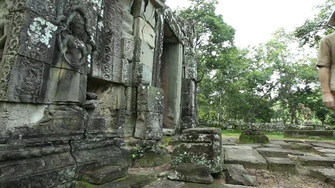 Young man exits ancient temple door, in Prasat Kravan Stock Footage 76381628
