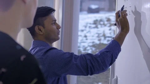 Young man explaining to his classmate in the classroom Stock Footage 74624561