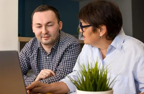Young man explaining his senior mom how to use appliations on laptop. Stock Photos