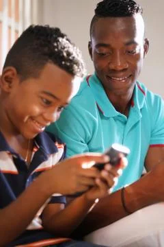 Young Man Explaining Mobile Phone Internet To Son At Home Stock Photos