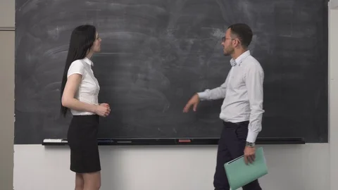 Young man is explaining something near the blackboard to a woman Stock Footage 77170061