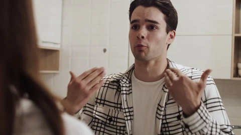 Young man explaining something to woman in kitchen Stock Footage 284026923