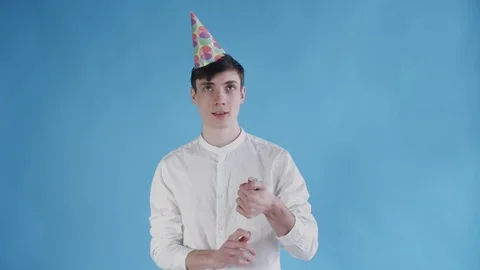 Young man exploding confetti cracker on a blue background. Stock Footage 108590465