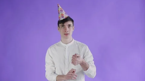 Young man exploding confetti cracker on a purple background. Stock Footage 108591895