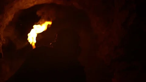 Young man exploring a dark cave with a burning torch Stock Footage 168064121