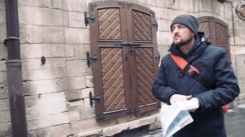 Young man exploring map while standing near old building and go away. Stock Footage 86192544