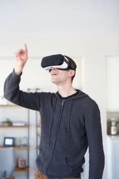 Young man exploring virtual reality with VR headset goggles - pointing Stock Photos