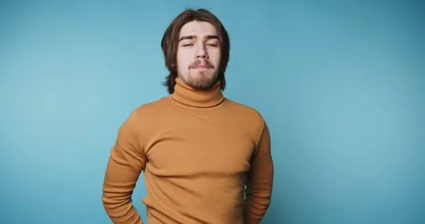 Young man expresses different emotions against a blue background while wear.. 動画素材 328249982
