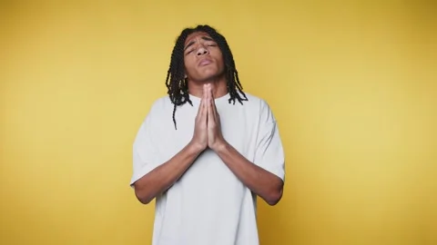 Young man expresses gratitude while standing against a bright yellow wall i.. 스톡 동영상 328248959