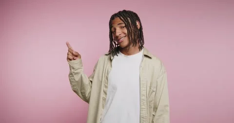 Young man expresses joy and surprise with playful gestures in a pink backdrop Vídeo Stock 329112397
