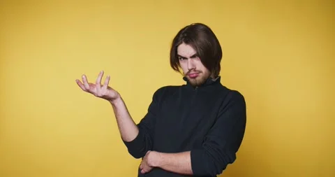 Young man expresses puzzlement with a questioning hand gesture on yellow ba.. Stock Footage 314336940