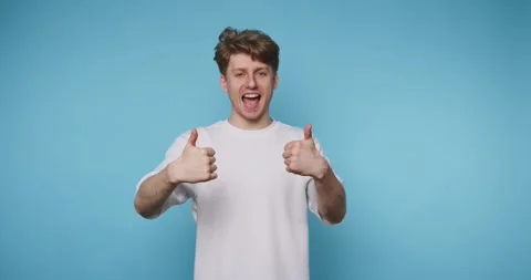 Young man exuberantly shows two thumbs up, expressing positivity and approv.. Stock Footage 313281121