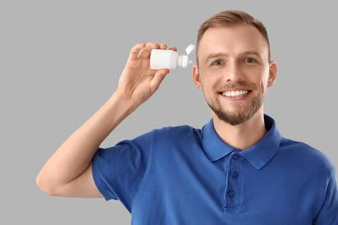 Young man with eye drops on light background Stock Photos
