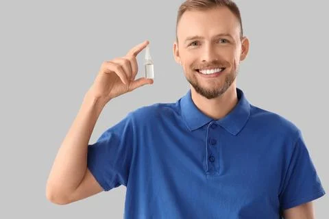 Young man with eye drops on light background Stock Photos