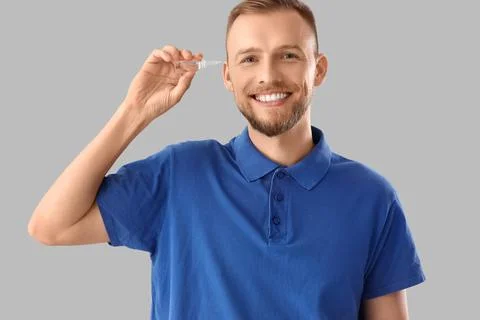 Young man with eye drops on light background Stock Photos
