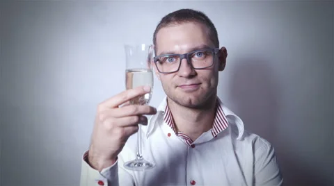 Young man in eye glasses drinking champagne over grey background. 動画素材 44912217