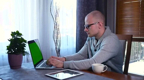 Young man in eyeglases using his laptop at home. Green screen. Stock Footage 61281673