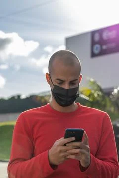 Young man with face mask checking his mobile phone and speaking in the park Stock Photos