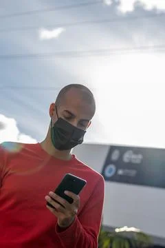 Young man with face mask checking his mobile phone and speaking in the park Foto stock