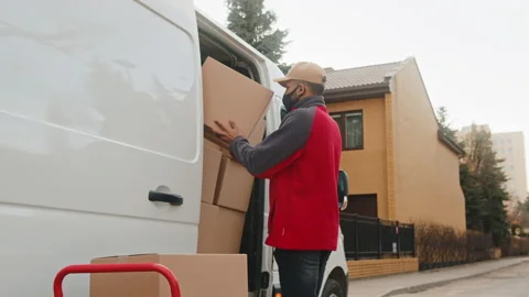 Young man with face mask loading van with cardboard boxes Stock Footage 152568135