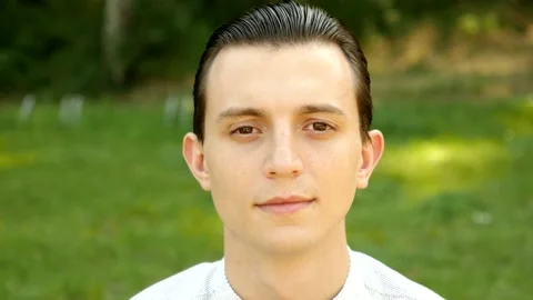  Young Man Face Portrait sitting on a Green Grass in a Summer Park Stock Footage 139561376