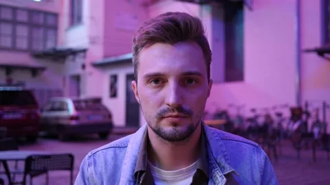 Young Man Face Portrait smiling on a Night City Street under Neon Lamps Stock Footage 139869730