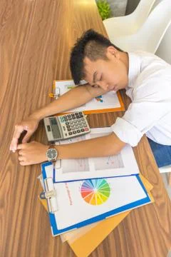 Young man fall asleep on working desk with financial documents Stock Photos