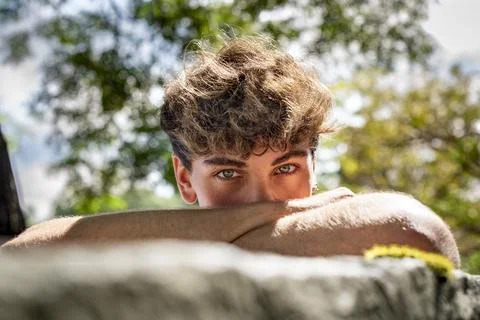 Young man falls his head down on his arms, smiling and looking at the camer.. Foto stock