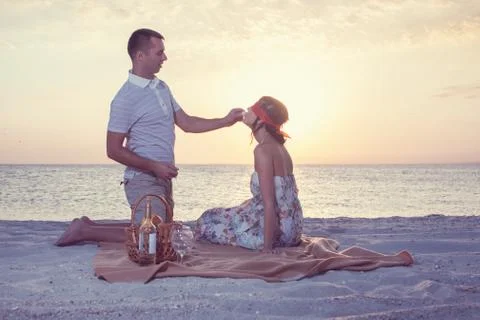 Young man feeding chocolade candy his girlfriend with covered eyes during sun Stock Photos