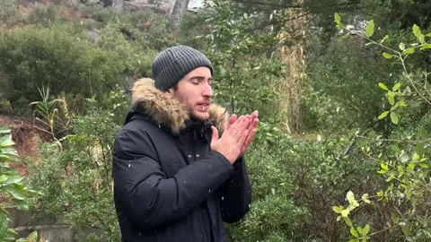 Young man feeling cold while snowing in the forest Stock Footage 326236418